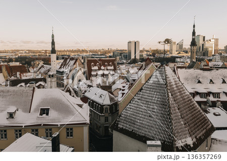 Snow covers rooftops in a city during winter in a historic town with modern buildings in view Snow covers rooftops in a city during winter in a historic town with modern buildings in view 136357269