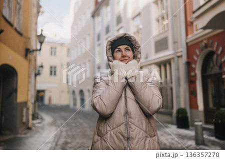 Woman enjoys cold weather while walking in an old city street during winter time Woman enjoys cold weather while walking in an old city street during winter time 136357270