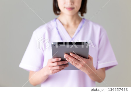 タブレットを持つ医療用スクラブ姿のミドル女性看護師 タブレットを持つ医療用スクラブ姿のミドル女性看護師 136357458