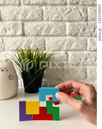 A woman's hand places a matching piece into a wooden puzzle 136358064