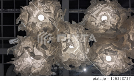 Crumpled paper lamps glow like soft clouds on dark ceiling, minimal abstract composition in neutral Cloud Dancer tone 136358737