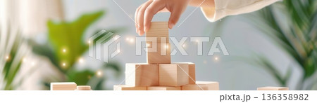 Hands of a child carefully stacking wooden blocks, representing learning and development 136358982