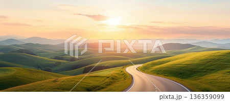 Serene winding road through rolling green hills, bathed in golden sunrise light. 136359099