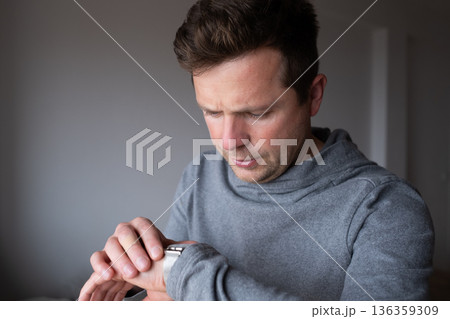Surprised man looking at his wristwatch realizing the clock has stopped working Surprised man looking at his wristwatch realizing the clock has stopped working 136359309