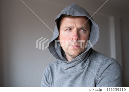 Lonely depressed man wearing a hoodie standing alone and hiding his face from the public Lonely depressed man wearing a hoodie standing alone and hiding his face from the public 136359310