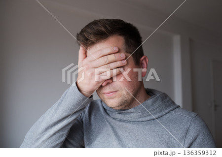 Stressed man closing his eyes tightly, refusing to face an unpleasant reality 136359312