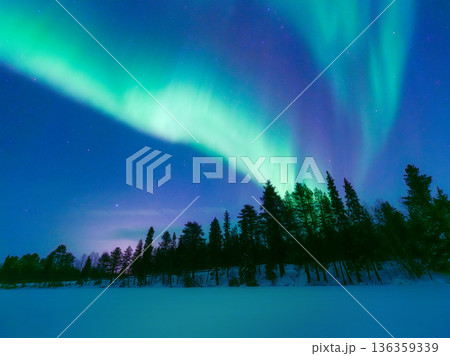 Panoramic horizontal view of the aurora borealis dancing over a snowy forest in Scandinavia. Panoramic horizontal view of the aurora borealis dancing over a snowy forest in Scandinavia. 136359339