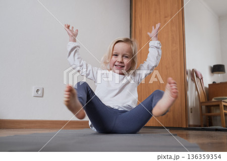 Little girl practicing yoga in Boat Pose Navasana on a mat. Little girl practicing yoga in Boat Pose Navasana on a mat. 136359354