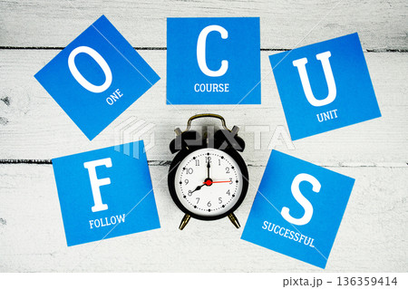 FOCUS Follow One Course Unit Successful with alarm clock on wooden background FOCUS Follow One Course Unit Successful with alarm clock on wooden background 136359414