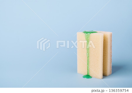 Cleaning sponge with liquid dishwashing detergent dripping on light blue background Cleaning sponge with liquid dishwashing detergent dripping on light blue background 136359754