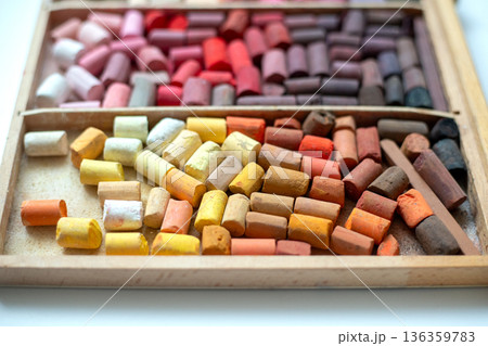 Set of soft pastel crayons in pink, red, and yellow in a wooden artist's box. Broken crayons, top view Set of soft pastel crayons in pink, red, and yellow in a wooden artist's box. Broken crayons, top view 136359783