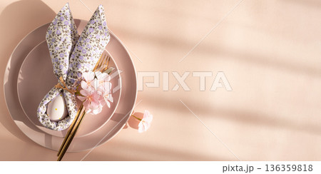 Easter Table Setting with Bunny Napkin and Decorated Egg. Festive Spring Arrangement on Pink Background Easter Table Setting with Bunny Napkin and Decorated Egg. Festive Spring Arrangement on Pink Background 136359818