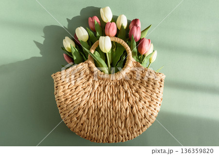 Tulip Bouquet in Straw Handbag.  Stylish Spring Floral Composition on Green Background 136359820