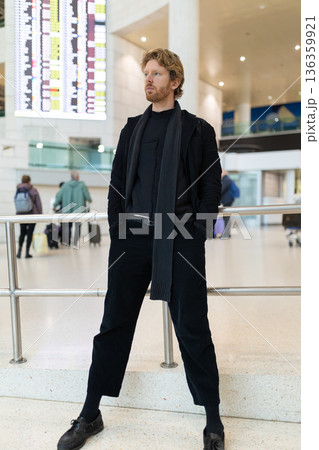 Man in black outfit standing in airport terminal Man in black outfit standing in airport terminal 136359921