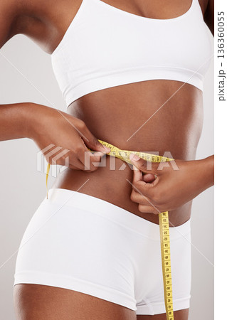 Tape measure, waist and stomach or body of woman for health and wellness on white background in studio. Fitness, progress and underwear of model on diet for weight loss goals, balance or motivation 136360055