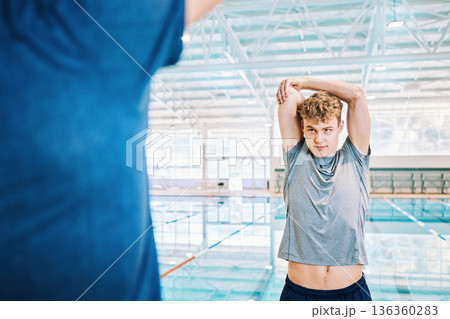 Man, swimmer or stretching arms with personal trainer for exercise, training or workout by indoor pool. Start, people or athlete in body warm up with fitness coach to get ready for swimming or sports Man, swimmer or stretching arms with personal trainer for exercise, training or workout by indoor pool. Start, people or athlete in body warm up with fitness coach to get ready for swimming or sports 136360283