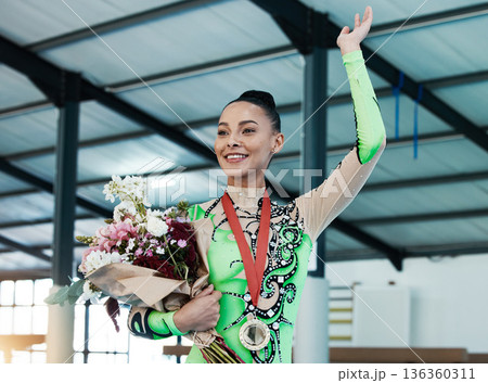 Woman, gymnastics and winner, medal and flowers, wave and happy with celebration and winning competition. Prize, reward and bonus, female champion on podium with gymnast and athlete smile with gift Woman, gymnastics and winner, medal and flowers, wave and happy with celebration and winning competition. Prize, reward and bonus, female champion on podium with gymnast and athlete smile with gift 136360311