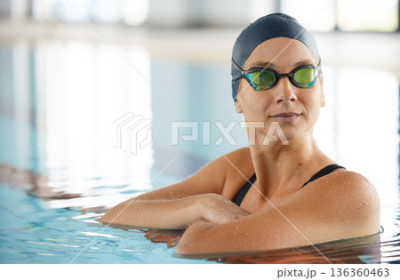 Swimming, thinking and a woman on a break in a pool from training, competition or fitness. Idea, serious and a professional athlete swimmer or girl in the water for exercise, cardio or sports 136360463