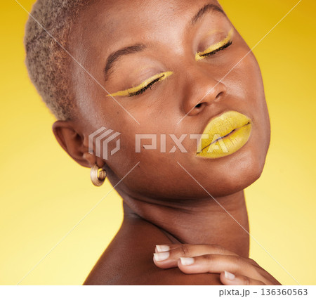 Cosmetic, art and woman in a studio with makeup eyeliner and lipstick for cosmetology. Beauty, creative and young African female model with a colorful glamour face routine by a yellow background. Cosmetic, art and woman in a studio with makeup eyeliner and lipstick for cosmetology. Beauty, creative and young African female model with a colorful glamour face routine by a yellow background. 136360563