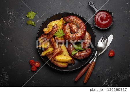 Fried coiled meat sausages roasted potatoes ketchup grilled bbq black plate barbecue Fried coiled meat sausages roasted potatoes ketchup grilled bbq black plate barbecue 136360587