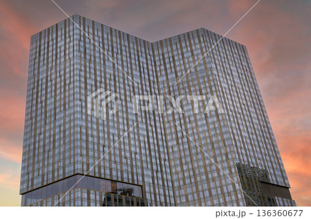 Sunset view of modern glass building in an urban area reflective windows architectural details 136360677