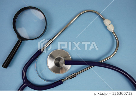 Stethoscope and magnifying glass with space copy for text on blue background Stethoscope and magnifying glass with space copy for text on blue background 136360712