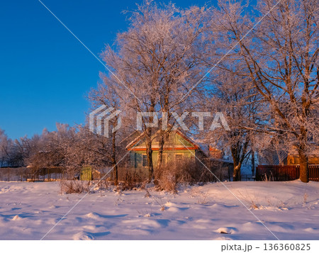 A charming wooden house stands in the snowy countryside 136360825