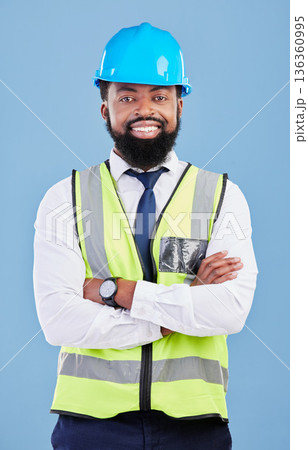 Happy black man, portrait and engineering with arms crossed in studio for safety inspection, maintenance and construction. Architect manager, contractor and industrial technician on blue background 136360995