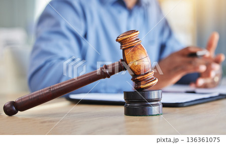 Closeup, lawyer and gavel of judge in office of trial, attention and meeting for justice in courtroom, law firm or table. Hammer, legal tool or attorney working at desk for consulting of constitution 136361075