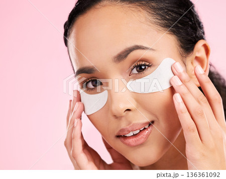 Beauty, face mask and eye patch of a woman with skin care, dermatology and natural glow. Portrait of a young female aesthetic model with cosmetics product for collagen and detox on a pink background Beauty, face mask and eye patch of a woman with skin care, dermatology and natural glow. Portrait of a young female aesthetic model with cosmetics product for collagen and detox on a pink background 136361092