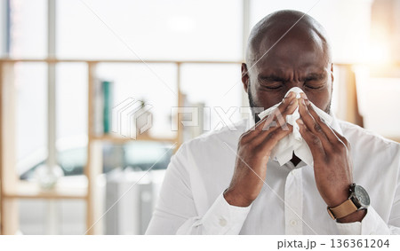Sick, tissue and businessman blowing his nose in the office with cold, flu or sinus allergies. Illness, medical and professional young African male person with hayfever while working in the workplace 136361204