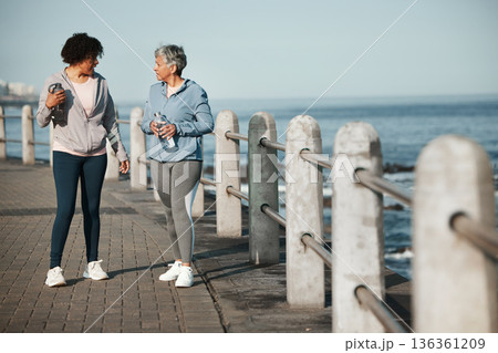 Fitness, walking and women by ocean talking for healthy lifestyle, wellness and cardio on promenade. Sports, friends and female people in conversation on boardwalk for exercise, training and workout Fitness, walking and women by ocean talking for healthy lifestyle, wellness and cardio on promenade. Sports, friends and female people in conversation on boardwalk for exercise, training and workout 136361209