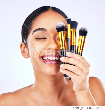 Makeup brush, beauty and cosmetics of a happy woman in studio for skincare, self care and cosmetology. Skin glow, shine and wellness of a female model with facial application tools for foundation Makeup brush, beauty and cosmetics of a happy woman in studio for skincare, self care and cosmetology. Skin glow, shine and wellness of a female model with facial application tools for foundation 136361233