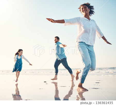 Mother, father and daughter on the beach to dance together while outdoor for travel or vacation in summer. Sunset, family or children and a girl having fun with her parents on the coast by the ocean 136361435