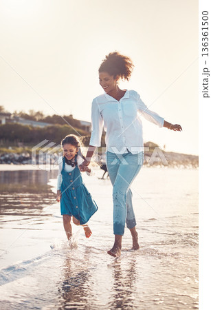 Fun, child and a mother running at the beach on a family vacation, holiday or adventure in summer. Young girl kid holding hands with woman outdoor with fun energy, happiness and love at sunset ocean 136361500