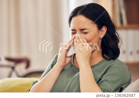 Sick, allergy and blowing nose with woman on sofa for virus, hayfever or illness. Healthcare, disease and allergies with person and sneezing with tissue in living room at home for influenza and sinus Sick, allergy and blowing nose with woman on sofa for virus, hayfever or illness. Healthcare, disease and allergies with person and sneezing with tissue in living room at home for influenza and sinus 136362087