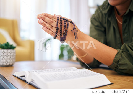 Hands, bible and home for prayer, rosary and mindfulness for faith, religion or reading with hope for future. Woman, praying and study holy book with cross for peace, mental health or worship to God 136362254