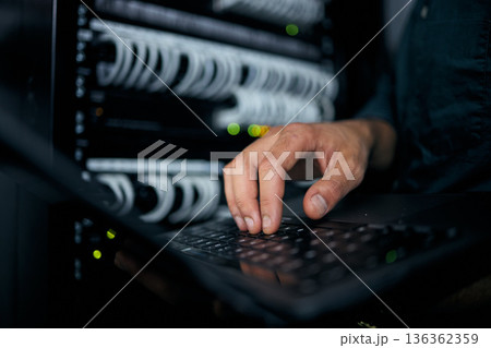 Hands, laptop and typing in server room, man and inspection with coding, analysis and night for programming. Information technology expert, computer and keyboard for database, solution or maintenance Hands, laptop and typing in server room, man and inspection with coding, analysis and night for programming. Information technology expert, computer and keyboard for database, solution or maintenance 136362359