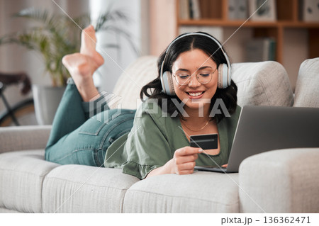 Woman, credit card and headphones on computer online shopping, e learning and fintech payment on sofa. Student or person relax with music subscription, banking services and home education on laptop 136362471