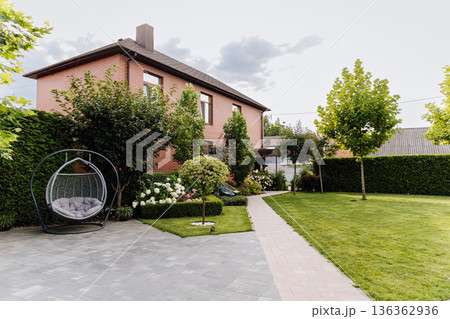 Modern brick house with landscaped backyard, patio pavers, lawn and hanging swing chair Modern brick house with landscaped backyard, patio pavers, lawn and hanging swing chair 136362936
