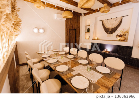 Cozy boho private dining room with long table setting and warm lighting 136362966