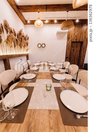 Cozy boho private dining room with pampas wall, set table and rattan lights 136362978