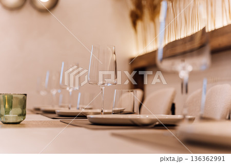 Elegant restaurant table setting with wine glasses and warm boho ambiance 136362991