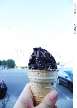 Girl holding ice cream in chocolate in her hand against the background of the sky 136363324