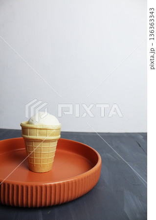 White Creamy Ice Cream in Waffle Cup on Plate on Gray Background White Creamy Ice Cream in Waffle Cup on Plate on Gray Background 136363343