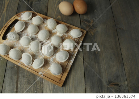Dumplings on a board. The process of cooking homemade food dumplings with space for copyspace text Dumplings on a board. The process of cooking homemade food dumplings with space for copyspace text 136363374
