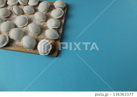 Frozen dumplings on a board on a blue background with space for copyspace text. Semi-finished products for vegetarians Frozen dumplings on a board on a blue background with space for copyspace text. Semi-finished products for vegetarians 136363377