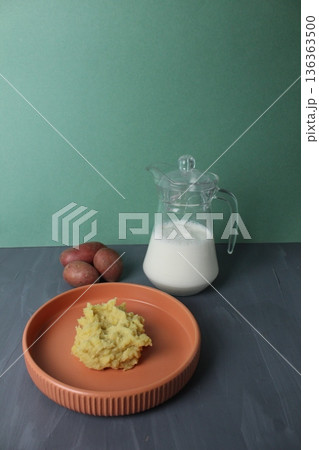 Mashed potatoes side dish of potatoes with milk in a jug on a gray background with space for text. Vegetarian Concept Vertical Photo 136363500