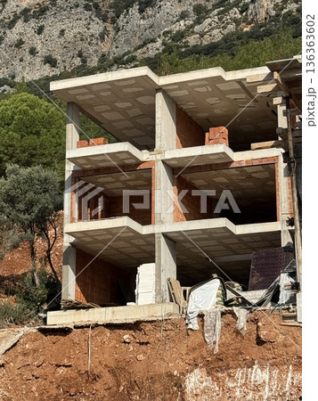 Construction of a concrete building structure with exposed brickwork in a rural landscape 136363602