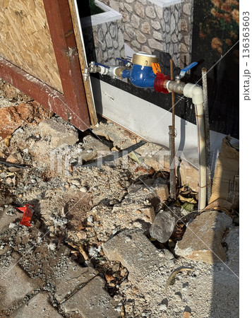 Water meter with pipes installed outdoors on rough, unfinished construction site background 136363603